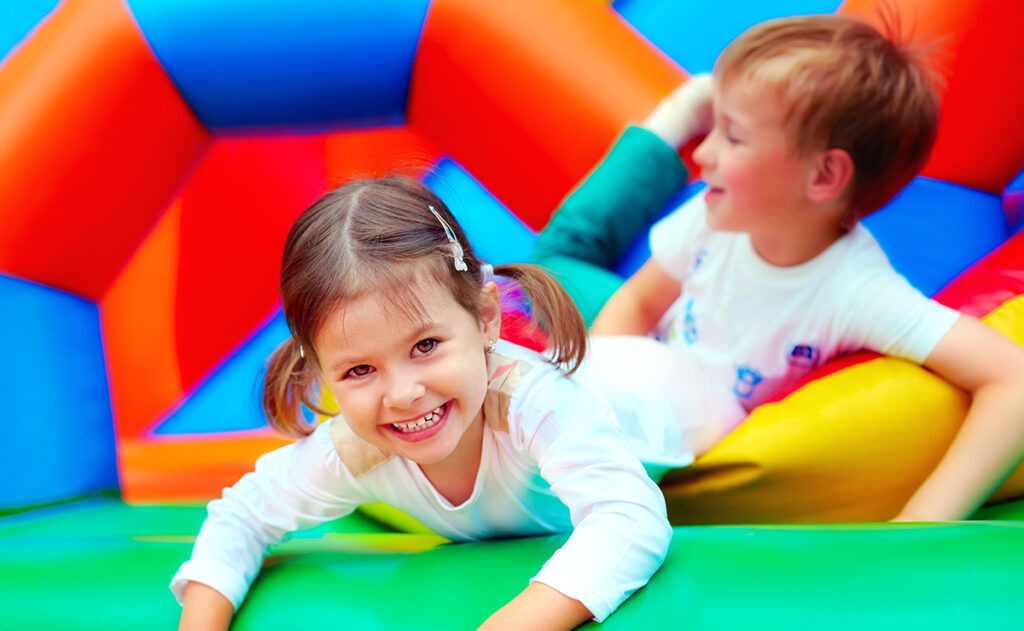 Two kids having fun playing inside a colorful inflatable, showing the excitement of bounce house rentals in Lehigh Acres, FL.