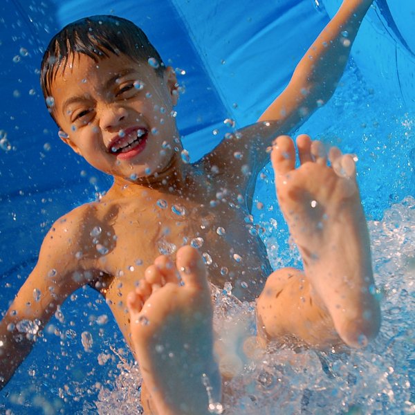 Smiling child splashing on an inflatable water slide during a summer event in Fort Myers, FL